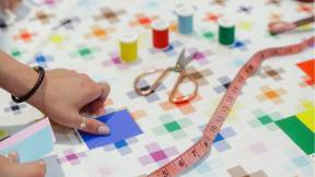 woman hand holding a piece of blue paper, next to scissors and colorful table