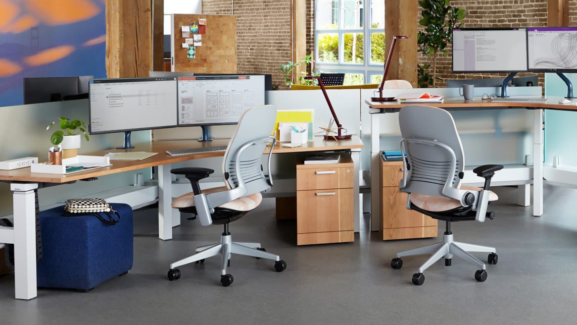 Collaborative space with wooden large desks and storages, two Leaps chairs with pattern on the cushion